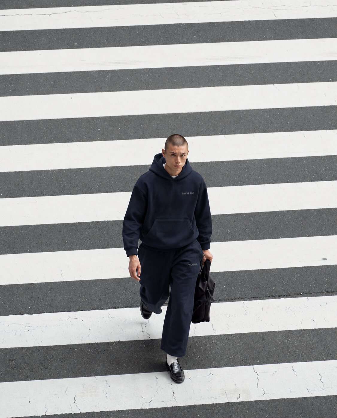 Model in the navy TALVESSO tracksuit crossing a zebra crossing